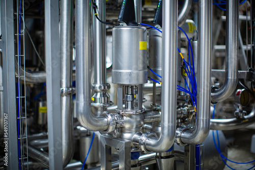 The process pipe valve is stainless at the in-process area of the pipeline flowing stainless food milk in a factory at the control room