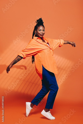 Fashionable black woman dancing in casual clothing in a studio photo