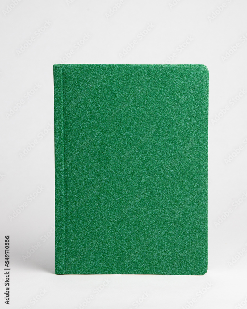 A green closed diary stands on a table on a white background. Front view A green closed diary stands on a table on a white background. Front view