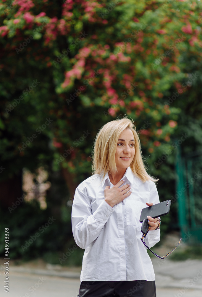 Portrait of a young business woman blonde smiling on a background of a city Portrait of a young business woman blonde smiling on a background of a city