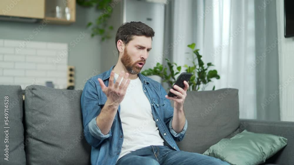 Annoyed young bearded man having problem with smartphone at home. Stressed male irritated using mobile phone with lost connection no signal error or mistake with app application Bad service concept
