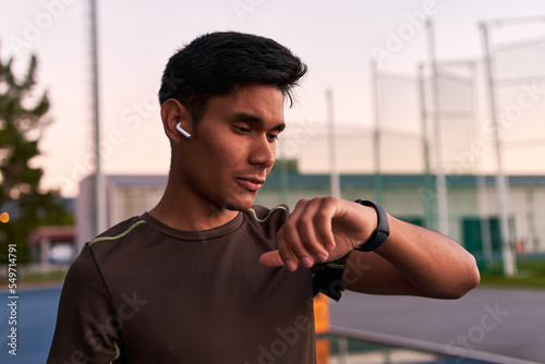 Young sportsman listening to music and checking his smartwatch © Distortion Media
