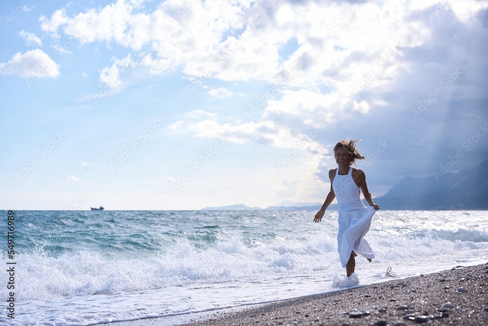 A front view of a young happy girl running on the beach. High quality photo