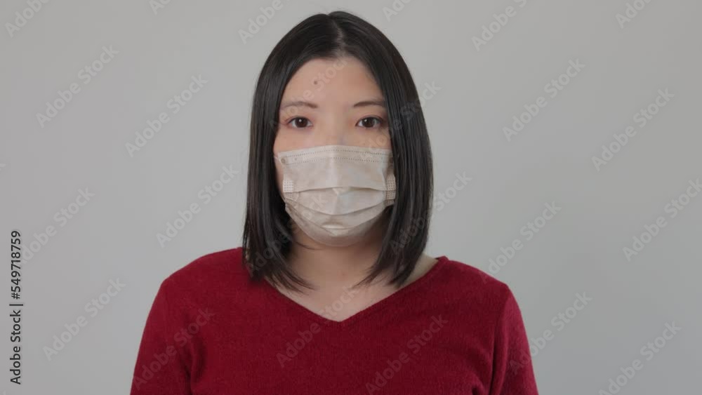 Asian young woman standing still with her mask on and stars the camera. Reluctant, Tired, Disappointed. 25P. Asian young woman standing still with her mask on and stars the camera. Reluctant, Tired, Disappointed. 25P.