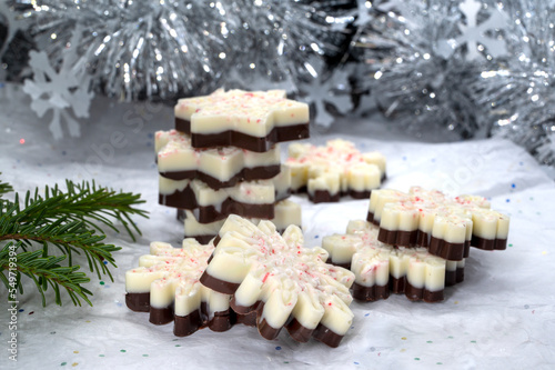 Holiday chocolate bark with dark and white chocolate on Christmas festive background. Christmas baking desert in snowflake shape 