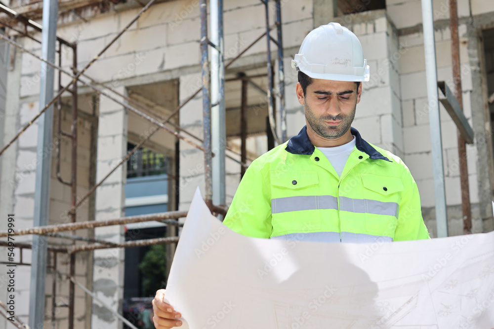 Caucasian technician civil engineer man or specialist inspector standing and planing real estate project work with blueprint while checking at Industrial building site. Construction concept Caucasian technician civil engineer man or specialist inspector standing and planing real estate project work with blueprint while checking at Industrial building site. Construction concept