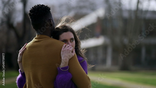 Interracial couple embrace outside. Young woman hugs partner photo