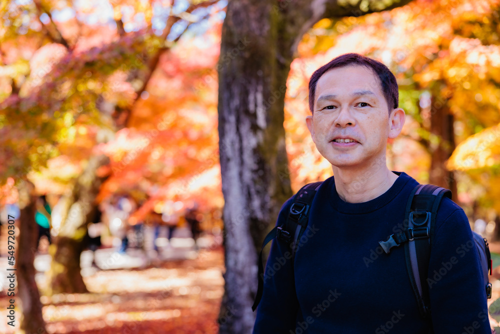 Middle-aged Asian man on a sightseeing tour of the autumn leaves in Kyoto, Japan. Middle-aged Asian man on a sightseeing tour of the autumn leaves in Kyoto, Japan.