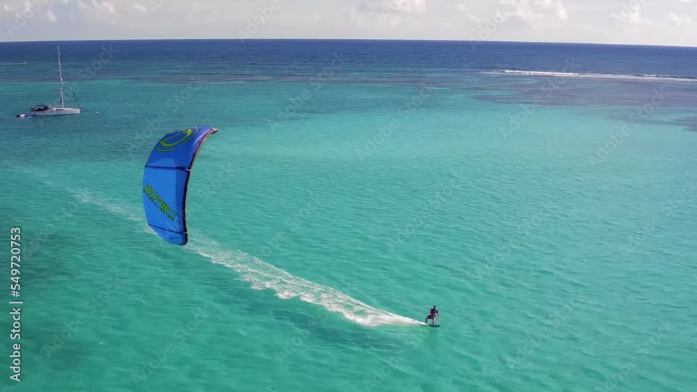 Kitesurfing in turquoise water of tropical beach paradise in warm waters at bright sunny day. Aerial view