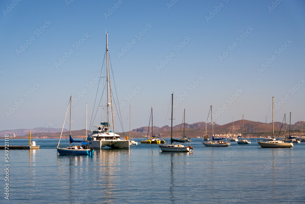 A large catamaran yacht (multi-hulled watercraft) enters the moorage off the Malecon (waterfront walkway) in La Paz, Baja de California Sur, Mexico. 