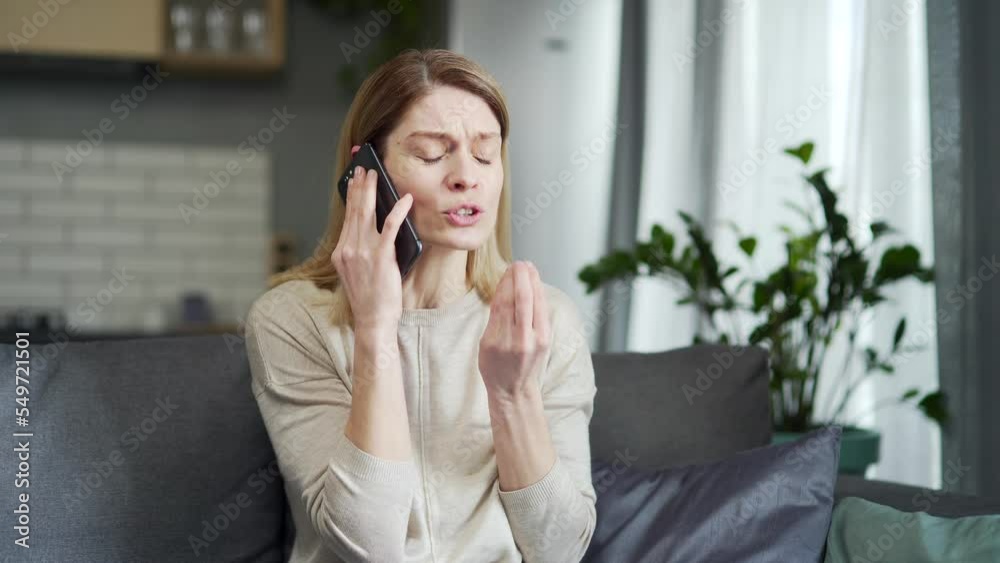Irritated arguing blond woman yelling at cellphone while sitting on the couch at home Angry nervous young female talking on a smartphone expressing negative emotion Bad conflict conversation Irritated arguing blond woman yelling at cellphone while sitting on the couch at home Angry nervous young female talking on a smartphone expressing negative emotion Bad conflict conversation