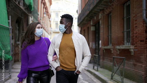 Couple wearing covid-19 face mask walking outside in street
