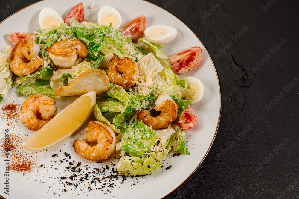 Tasty salad with shrimps, herbs and vegetables on black background Tasty salad with shrimps, herbs and vegetables on black background