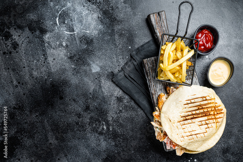 Turkish doner kebab in grilled pita bread with chicken meat. Black background. Top view. Copy space