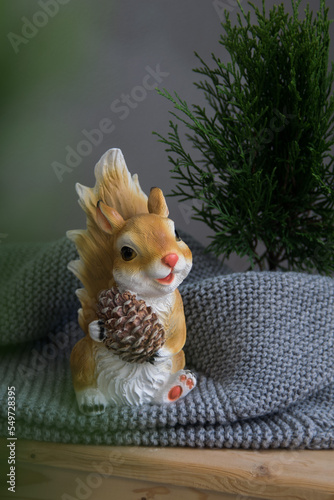 Cute toy plastic squirrel on grey backgground, selective focus. Home decor photo