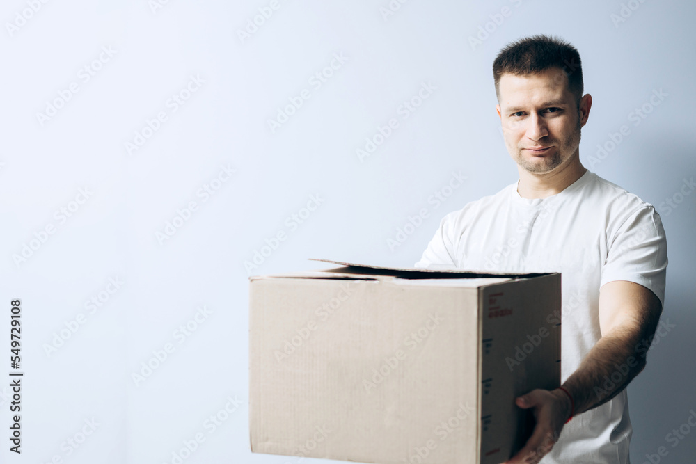European guy is holding a cardboard box for parcels. Courier with box ordered online. Person holding cardboard box in the hands. Mail delivery and post service, online shopping, e commerce concept. European guy is holding a cardboard box for parcels. Courier with box ordered online. Person holding cardboard box in the hands. Mail delivery and post service, online shopping, e commerce concept.