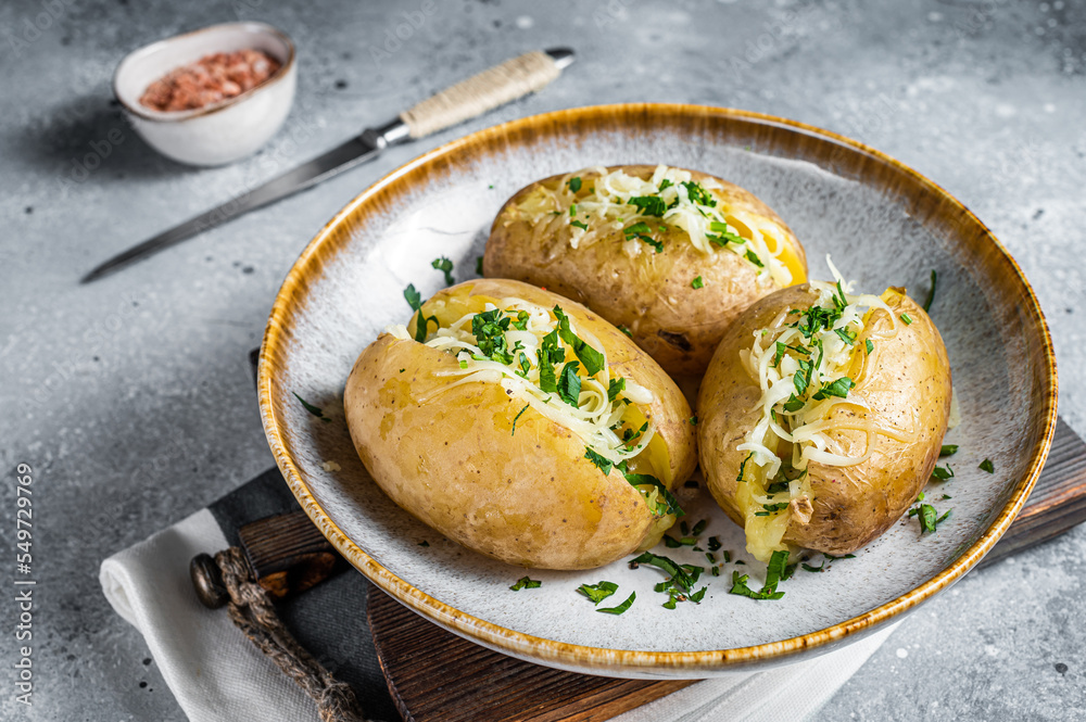 Baked Jacket potatoes with cheese and butter. Gray background. Top view