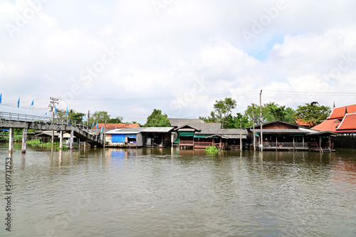 BANGKOK, THAILAND - NOVEMBER 20, 2022 : Wooden houses, Thai houses and buildings along the Chao Phraya River with white clouds and blue sky background, Town Ayutthaya Waterfront, Thailand.