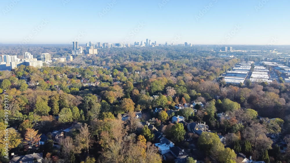 Aerial view lush green Brookwood Hills neighborhood with tree-lined streets, residential houses and midtown Atlanta skyscrapers in background