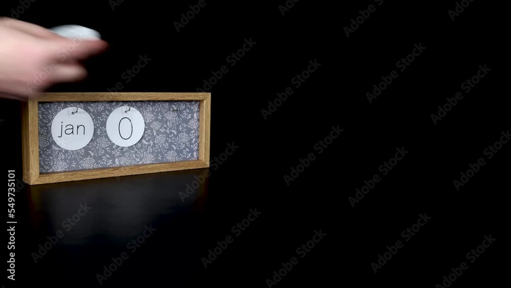 A wooden calendar block showing the date January 1st New Years Day with a mans hand putting on and taking off the metal discs with the date and month on them, filmed in 4k quality A wooden calendar block showing the date January 1st New Years Day with a mans hand putting on and taking off the metal discs with the date and month on them, filmed in 4k quality