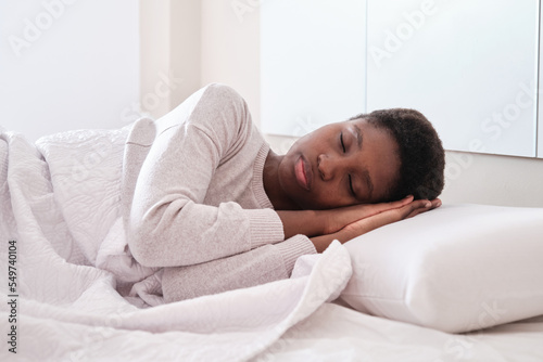 Black female sleeping in bed with hands under head