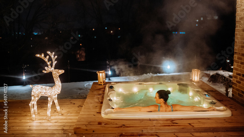 Foto Young woman enjoying outdoor bathtub in her terrace during cold winter evening