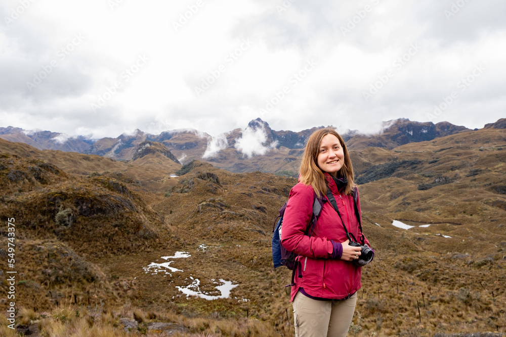 A female hiker smiling and holding her camera in the Cajas National Park in the highlands of Ecuador.