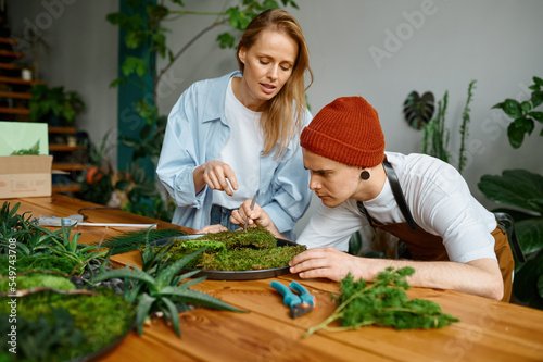 Woman florist teaching young hipster man decorator at art craft studio