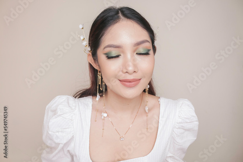 Close-up beauty face of Asian young model wearing ear accessories or ear cuff. Green eyes make-up look. Skincare beauty facial treatment, spa, female health concept.