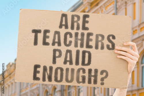 фотографія The question  Are teachers paid enough?  is on a banner in men's hands with blurred background
