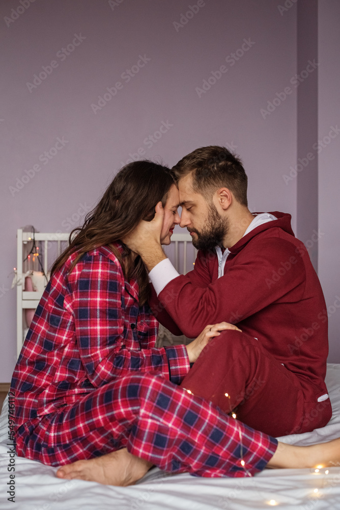 happy couple hugging and having fun together in bed in morning in red pajamas. happy couple hugging and having fun together in bed in morning in red pajamas.