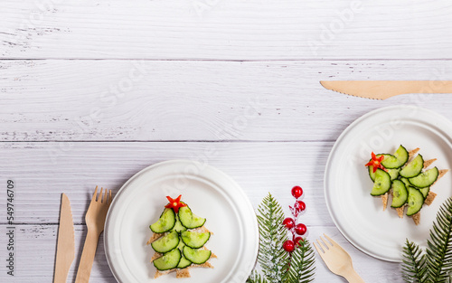 Sandwiches in the form of a Christmas tree with cream cheese and cucumber on a light wooden background, top view.