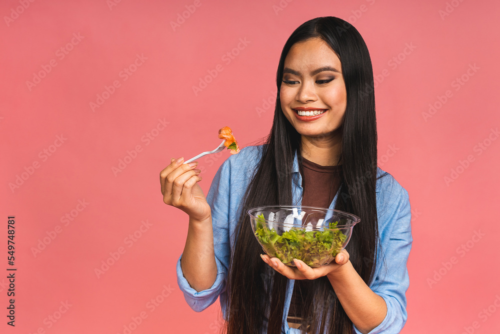 Clean eating diet concept. Asian woman holding vegeterian salad or bowl in take away container. Close up, copy space, isolated over pink background. Clean eating diet concept. Asian woman holding vegeterian salad or bowl in take away container. Close up, copy space, isolated over pink background.