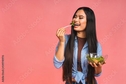 Clean eating diet concept. Asian woman holding vegeterian salad or bowl in take away container. Close up, copy space, isolated over pink background.