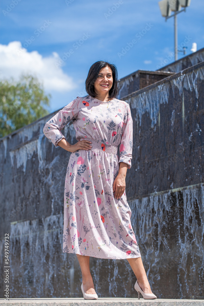 Obraz premium Portrait of a young beautiful woman posing against the backdrop of a city fountain