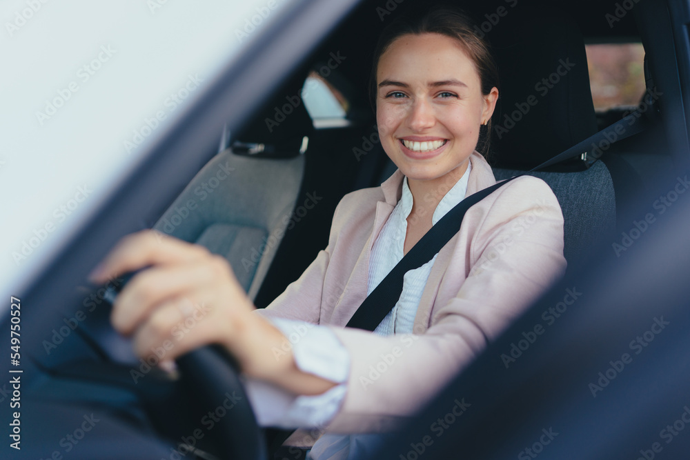 Excited young woman sitting in her car, prepared for driving.