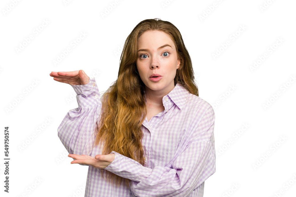 Young caucasian redhead woman isolated shocked and amazed holding a copy space between hands. Young caucasian redhead woman isolated shocked and amazed holding a copy space between hands.