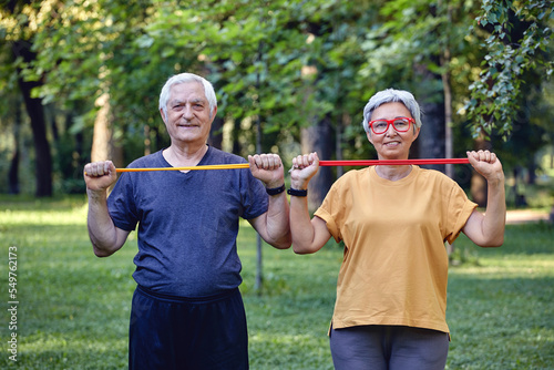 Senior couple doing exercises outdoor using resistance rubber bands