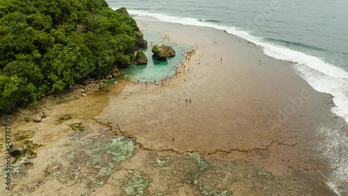 Rocky shore at low tide with swimming pools and tourists. Magpupungko natural rock pools. Siargao, Philippines. photo