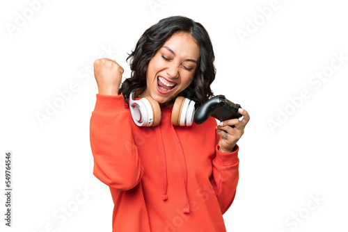 Young Argentinian woman playing with a video game controller over isolated background celebrating a victory