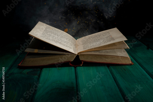 Old book on green table with smoke and sparkles - learning concept