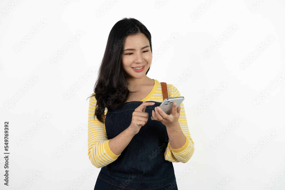Portrait Charming young Asian businesswoman owner wearing an apron holding smartphone isolated on white background. Looking at the camera. Portrait Charming young Asian businesswoman owner wearing an apron holding smartphone isolated on white background. Looking at the camera.