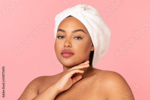 Beauty care concept. Portrait of african american chubby lady posing with wrapped towel on head during selfcare routine
