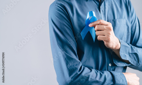 men hands holding Blue ribbon for supporting people living and illness, Colon cancer, Colorectal cancer, Child Abuse awareness, world diabetes day, International Men's Day