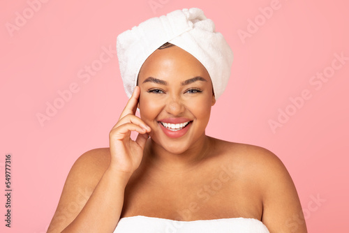 Beautiful african american oversize woman with white towel on head, enjoying her young beauty and smiling at camera