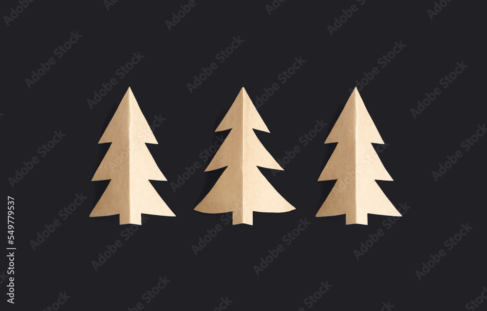 Obraz premium Three craft paper Christmas trees on a dark background