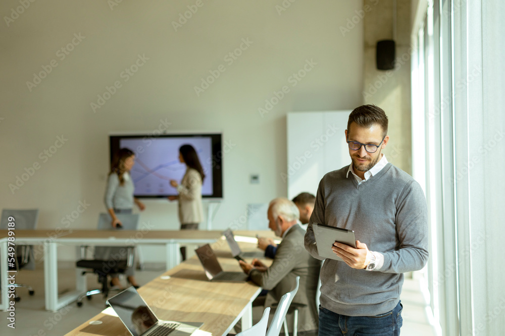 Obraz premium Young modern businessman using digital tablet in the office