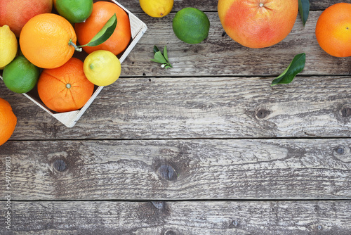 Citrus fruit top frame or border on wooden background. Oranges, lemons, grapefruits and limes with leaves on wooden table. Copy space. View from above.