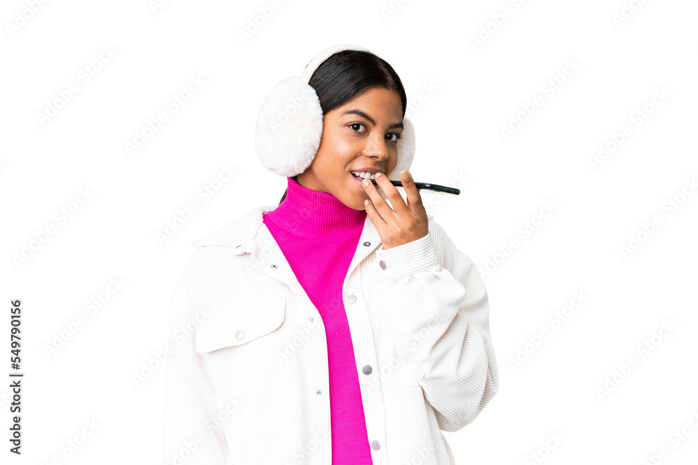 Young African American woman wearing winter muffs over isolated chroma key background keeping a conversation with the mobile phone Young African American woman wearing winter muffs over isolated chroma key background keeping a conversation with the mobile phone