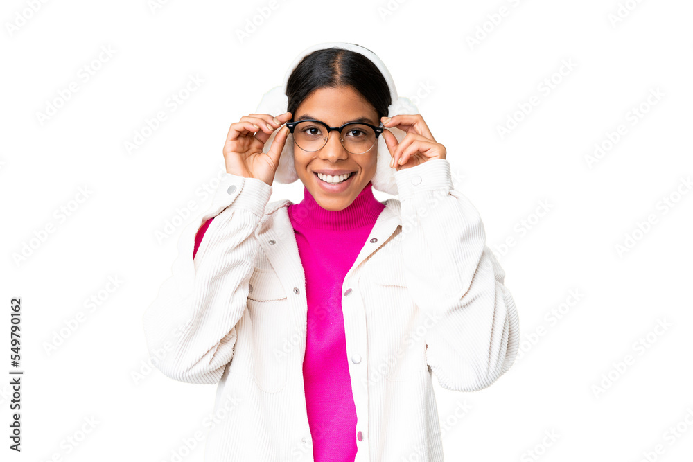 Young African American woman wearing winter muffs over isolated chroma key background with glasses and surprised Young African American woman wearing winter muffs over isolated chroma key background with glasses and surprised